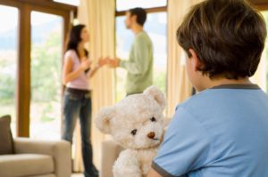 Graphic of divorcing couple in the background with focused foreground of of child holding a teddy bear. John Kinney and Jill Mason of Kinney Mason PC LLO, Attorneys at Law are divorce and family law attorneys with years of experience.